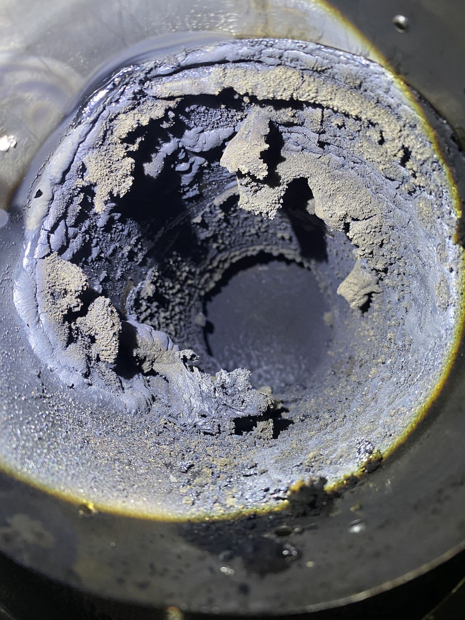 Close-up of heavy creosote buildup inside a flue before cleaning