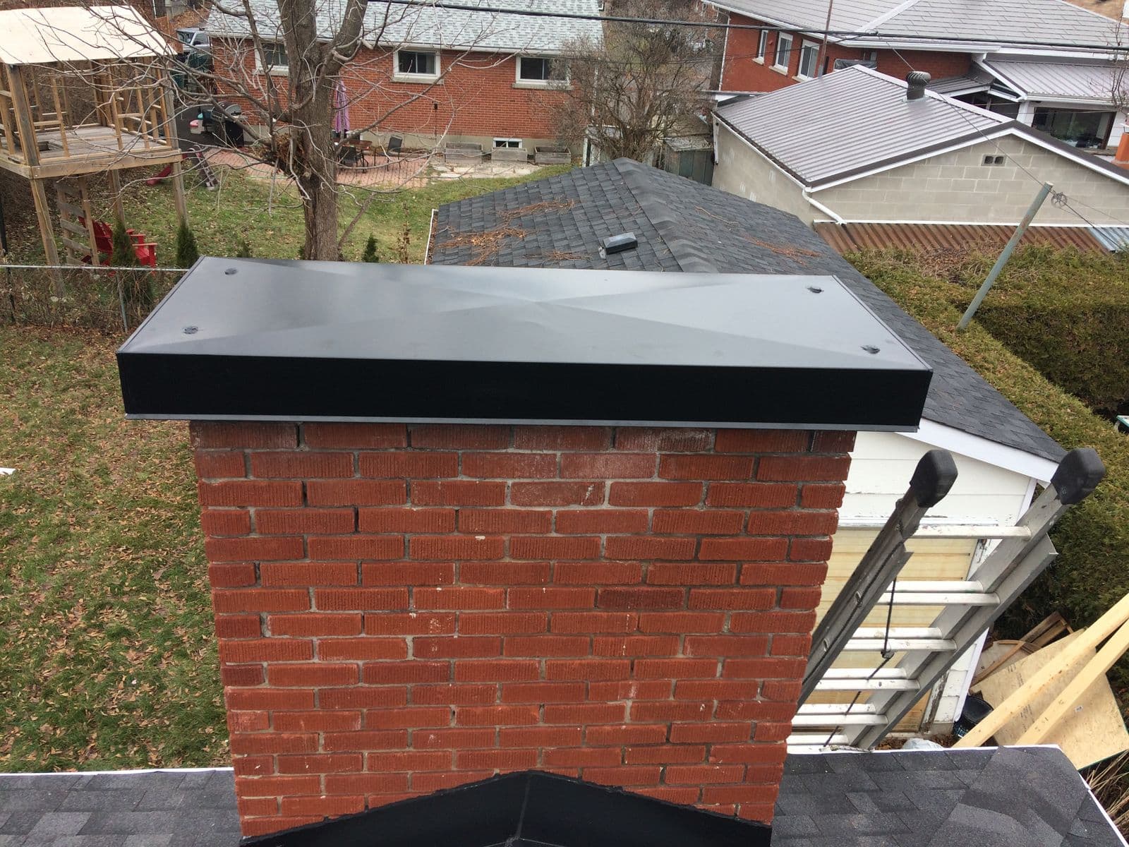 A finished flat black chase cap on a brick chimney