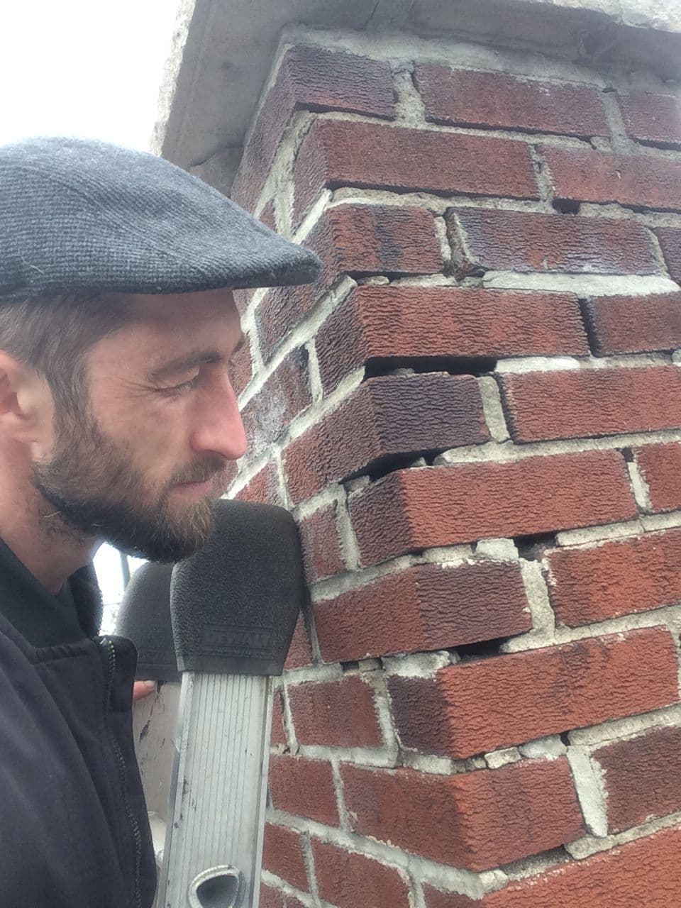 Jacob inspecting cracked mortar on a chimney up close
