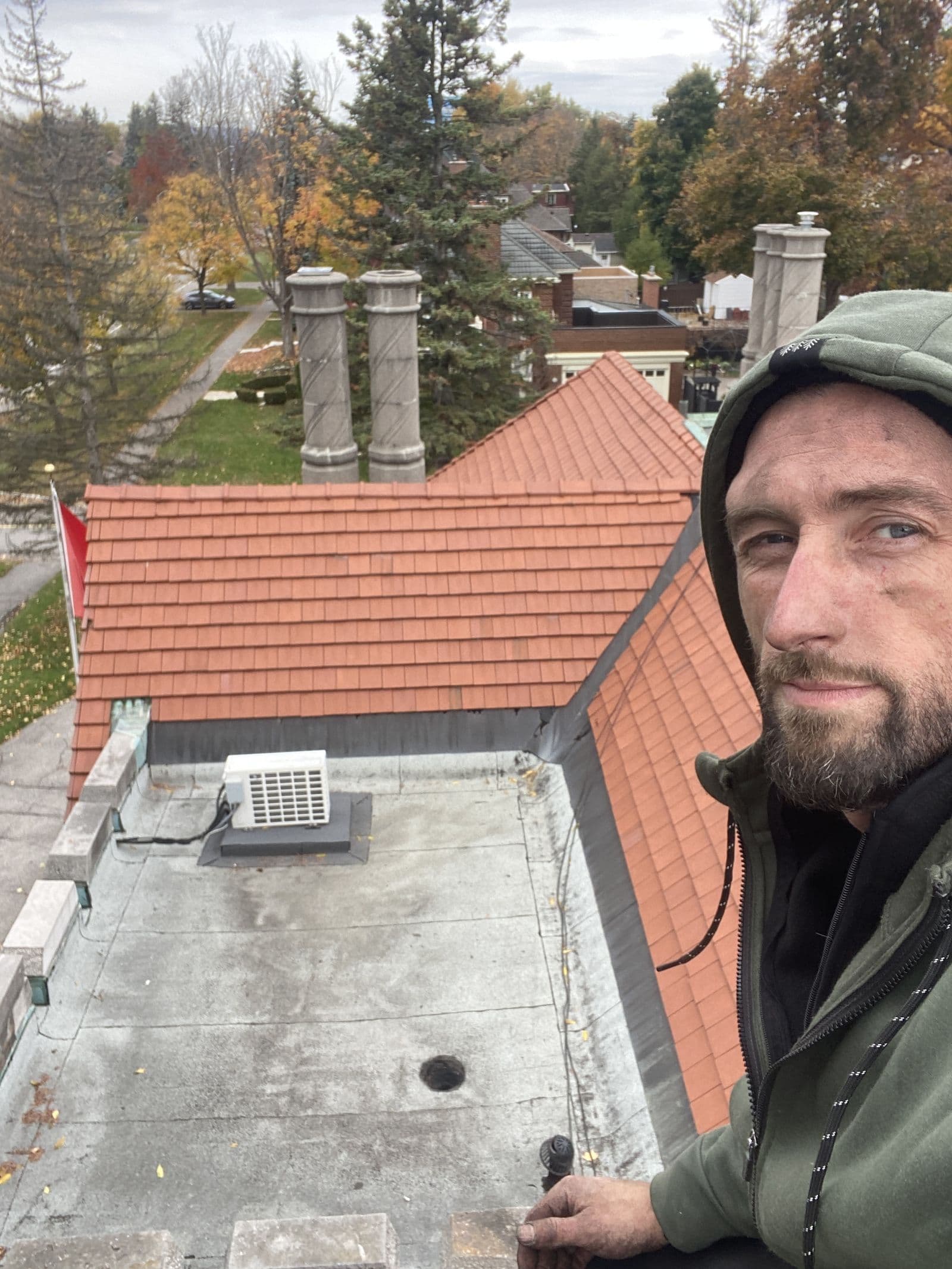 Jacob on a tile roof with ornate chimney pots in the background