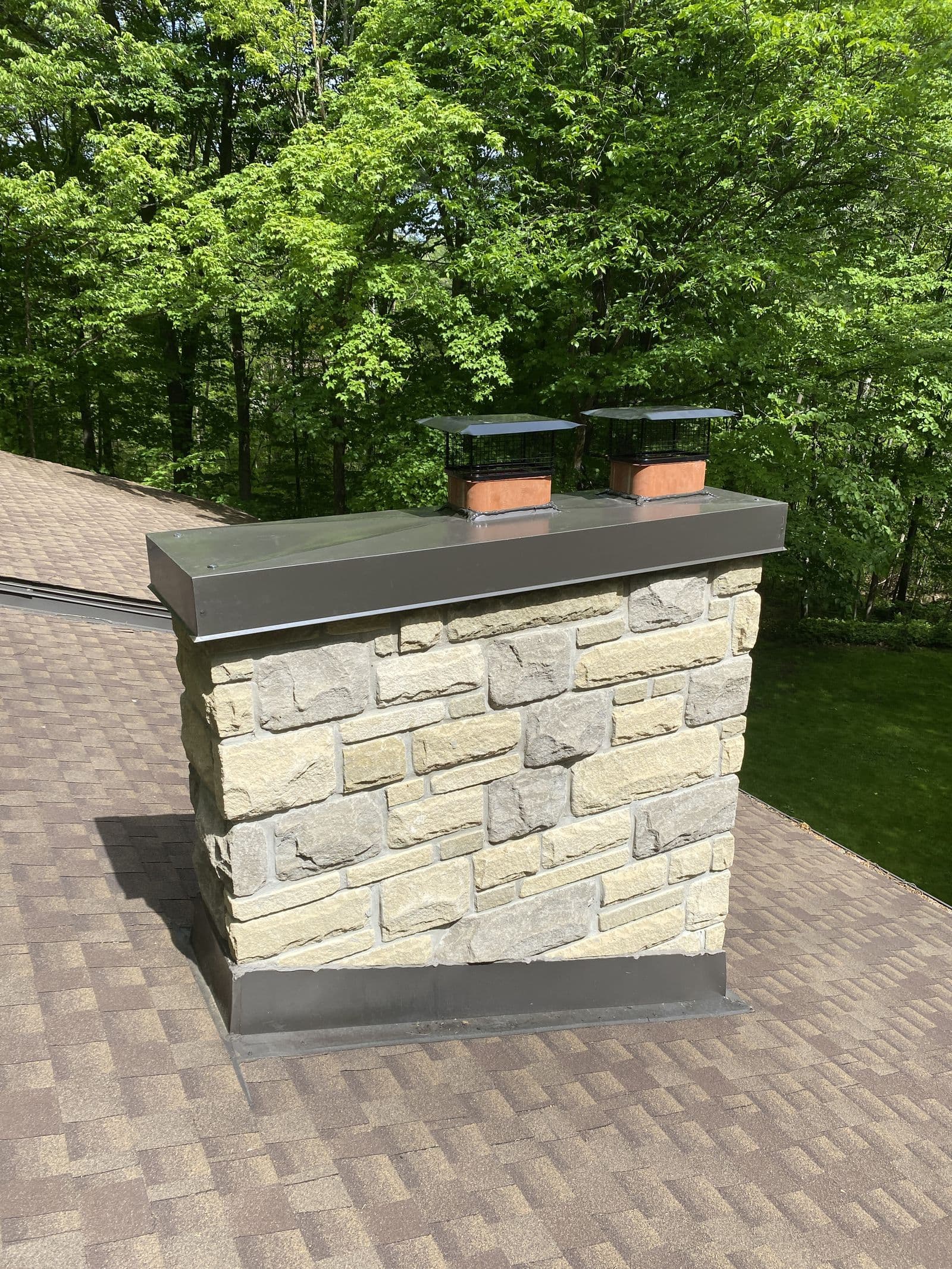 The same stone chimney with a new chase cover and two rain caps